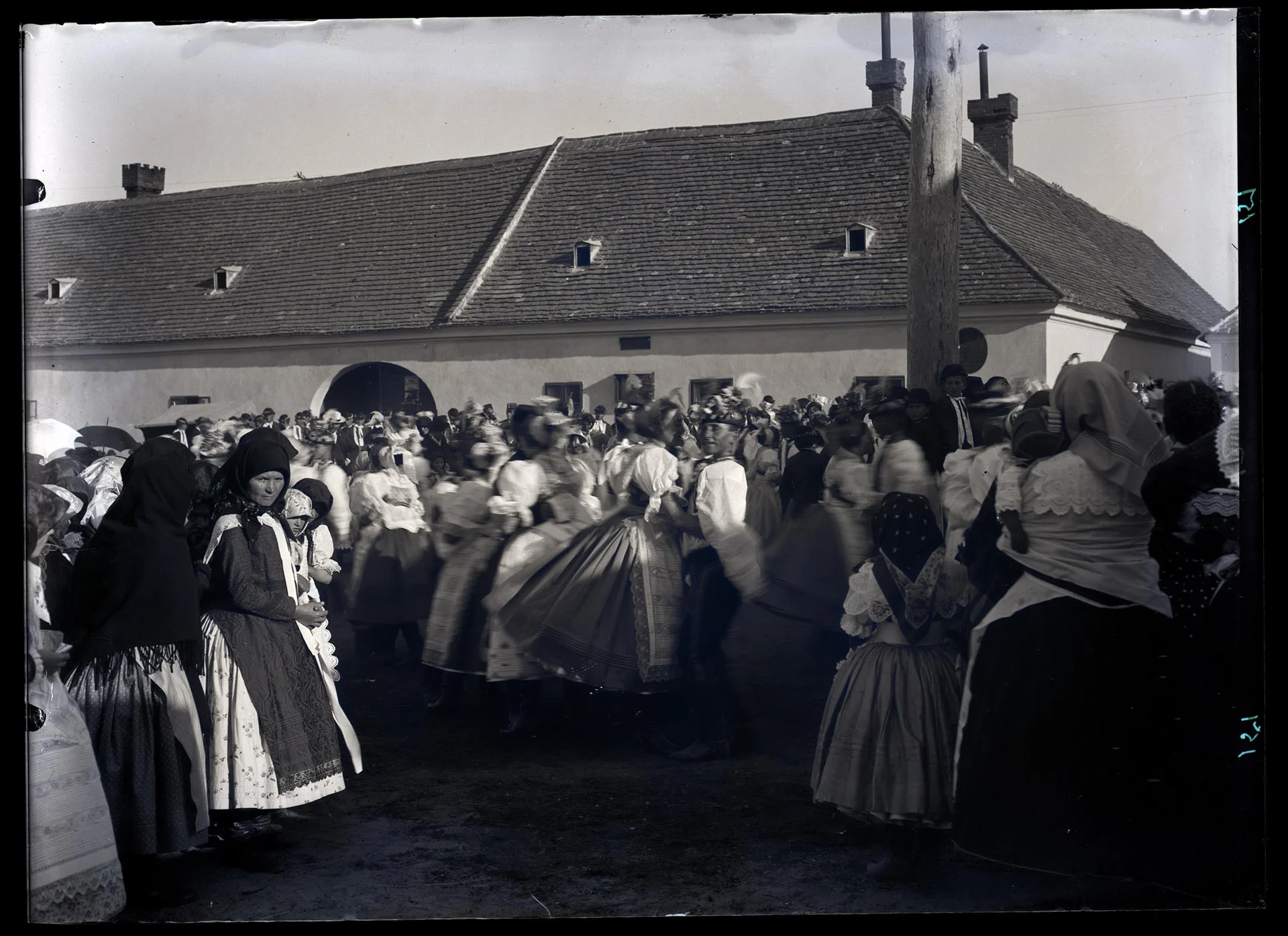 Obrázek "U máje" o hodech v Lanžhotě, tančící krojované páry, v pozadí hostinec