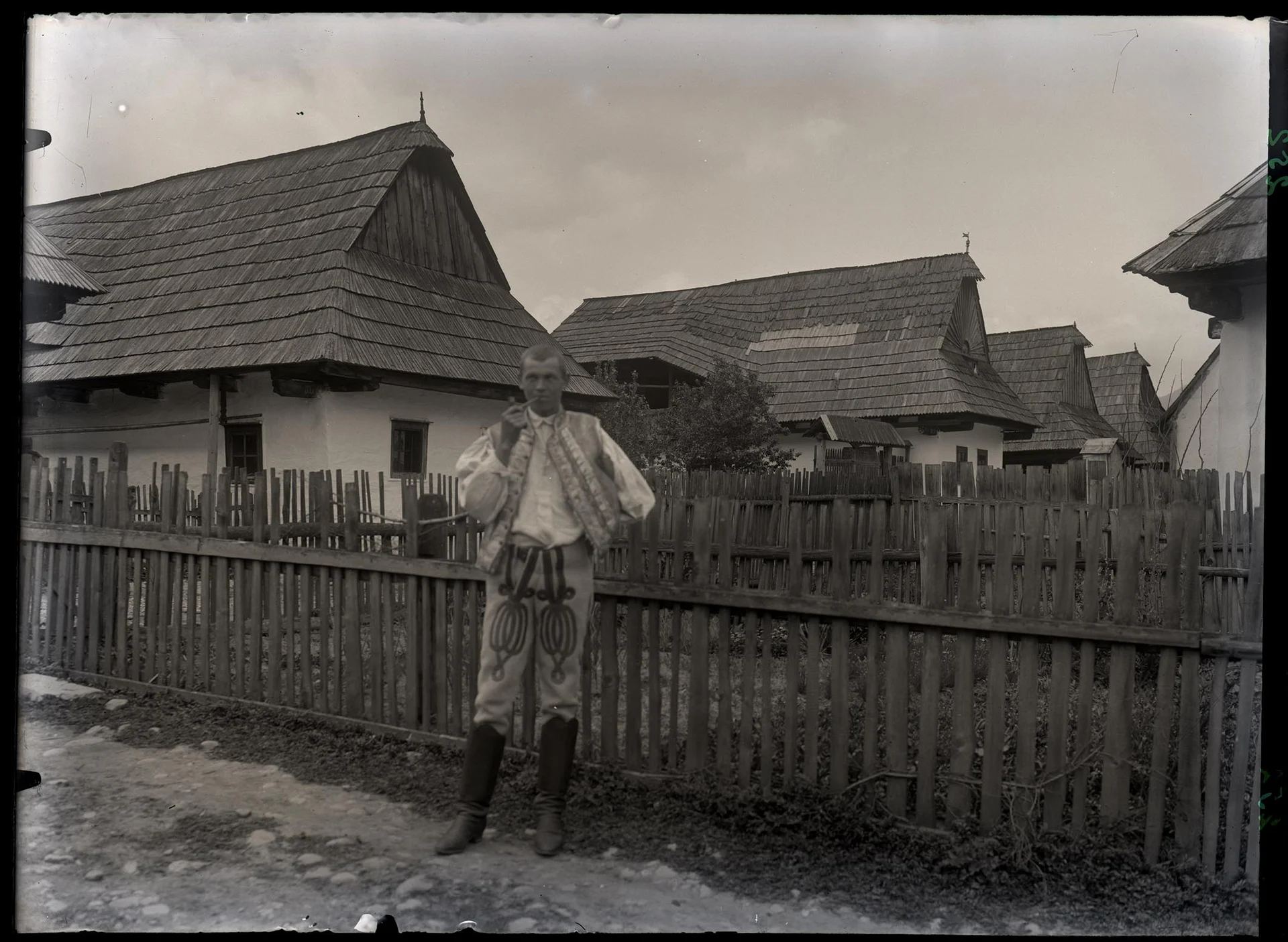 Obrázek Chalupy roubené ve Velké vsi, v popředí před plaňkovým plotem Ondřej Paclík v kroji s dýmkou, z č. 171.
