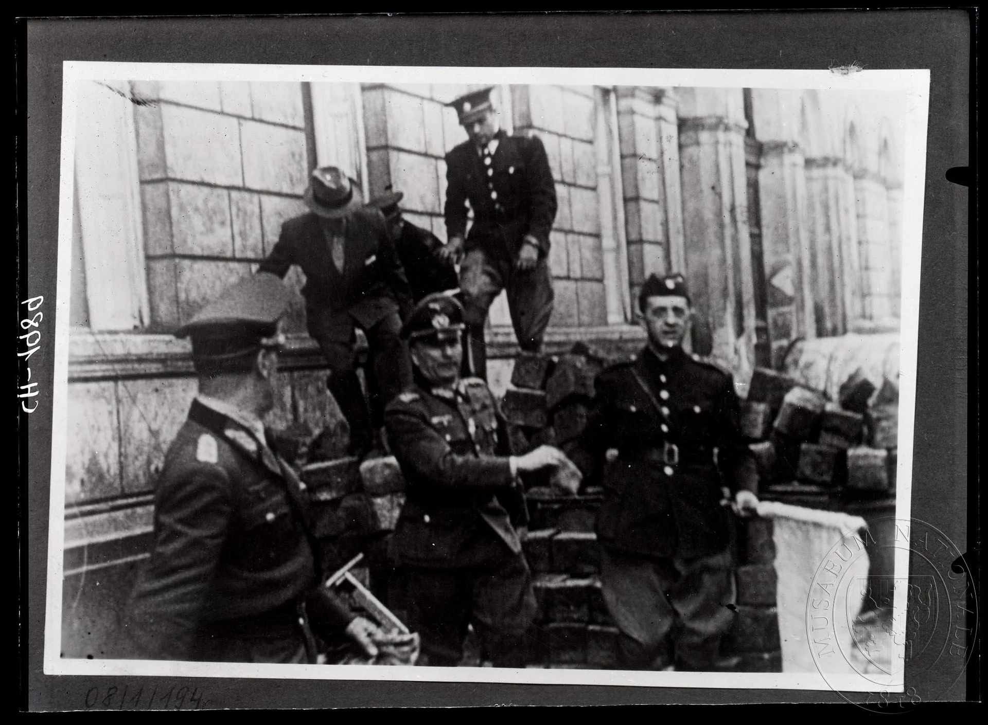 Obrázek Fotografie, vojáci a civilisté přecházejí barikádu.